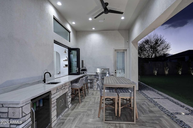 view of patio featuring ceiling fan, area for grilling, wine cooler, a grill, and a wet bar