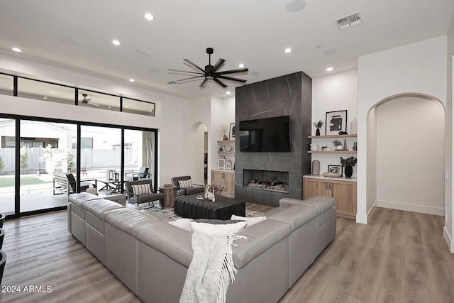 living room featuring light hardwood / wood-style floors, ceiling fan, and a fireplace