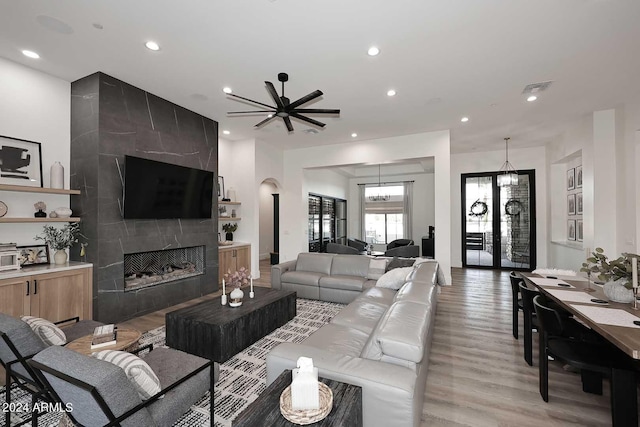 living room featuring light wood-type flooring, a tiled fireplace, and ceiling fan