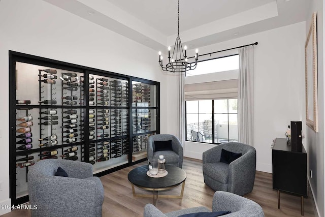 interior space with wood-type flooring, an inviting chandelier, and a raised ceiling