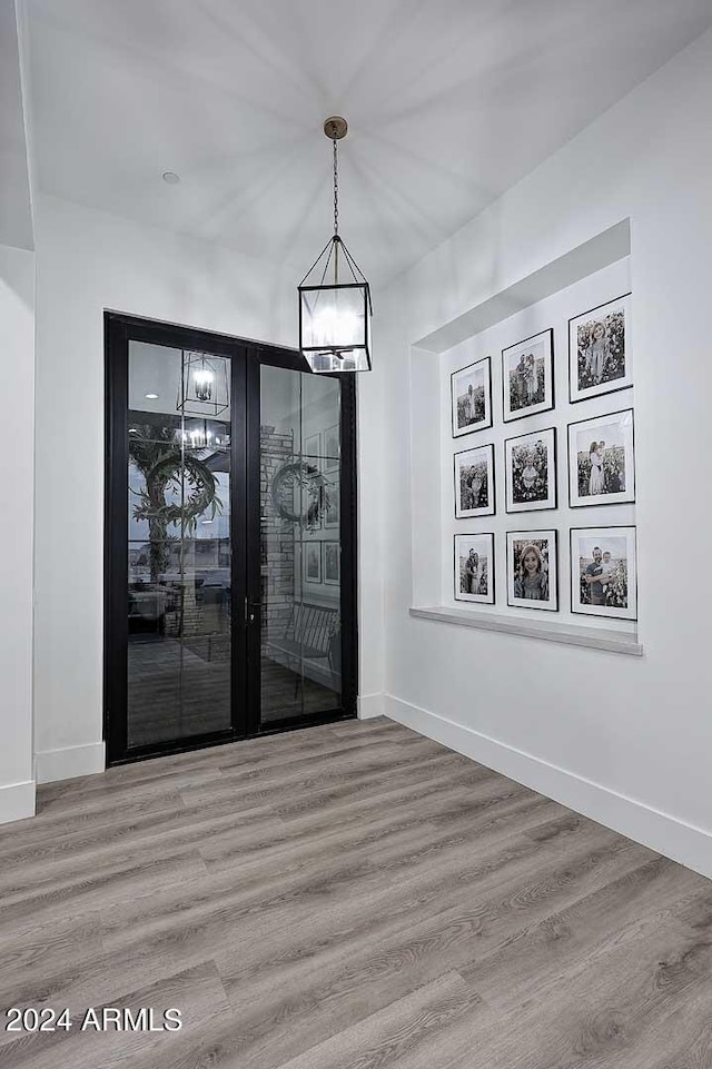 empty room with an inviting chandelier and wood-type flooring