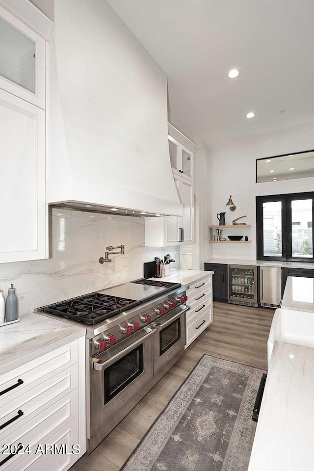 kitchen with white cabinets, premium range hood, dark hardwood / wood-style floors, and double oven range