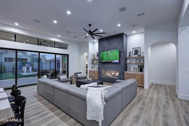 living room with ceiling fan, a fireplace, and light hardwood / wood-style floors