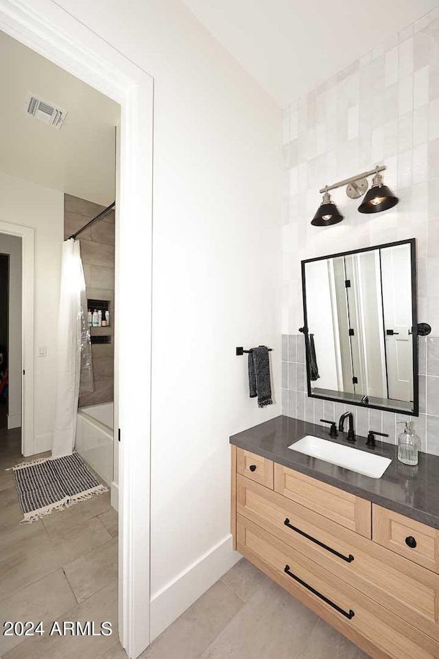 bathroom with backsplash, shower / tub combo with curtain, and vanity