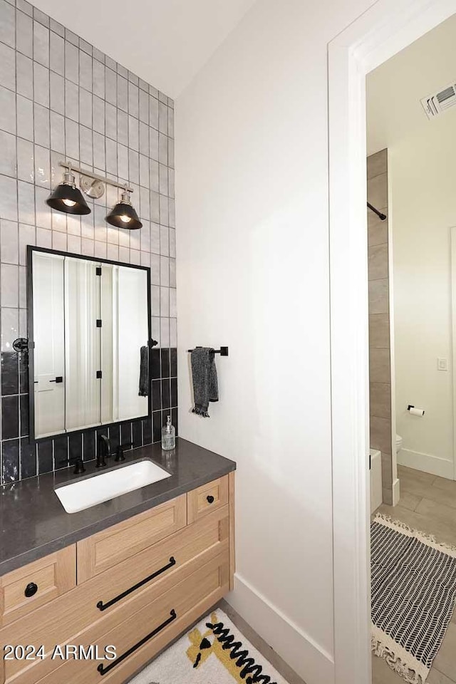 bathroom with tile patterned flooring, decorative backsplash, a shower, vanity, and toilet