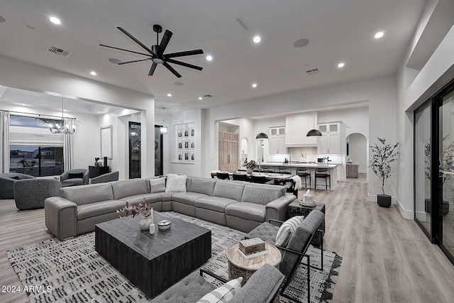 living room featuring ceiling fan with notable chandelier and light hardwood / wood-style floors