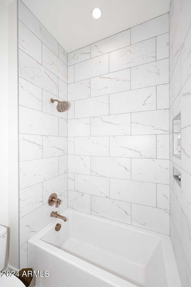 bathroom with tiled shower / bath combo and toilet