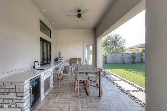 view of patio / terrace featuring area for grilling, sink, ceiling fan, and wine cooler