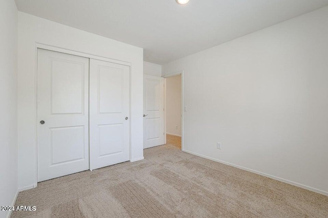 unfurnished bedroom with carpet, a closet, and baseboards