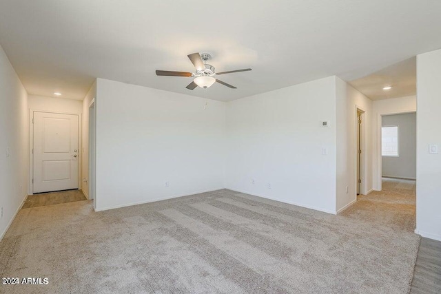 spare room with light carpet, baseboards, and a ceiling fan