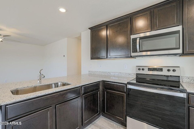 kitchen featuring a sink, light stone counters, appliances with stainless steel finishes, and dark brown cabinets