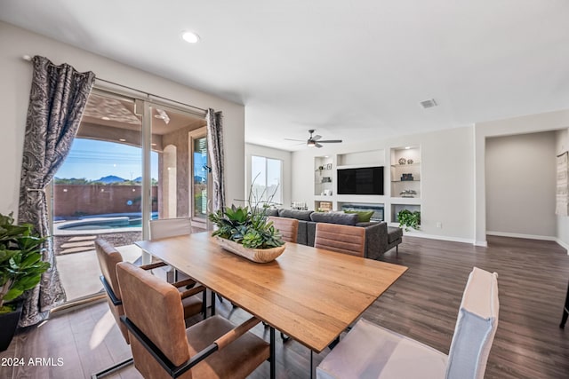 dining room with built in features, ceiling fan, and dark wood-type flooring