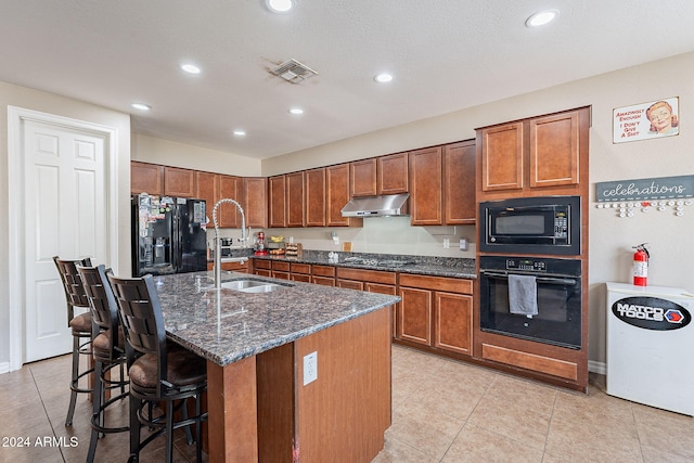 kitchen with a breakfast bar, a kitchen island with sink, sink, black appliances, and light tile patterned floors