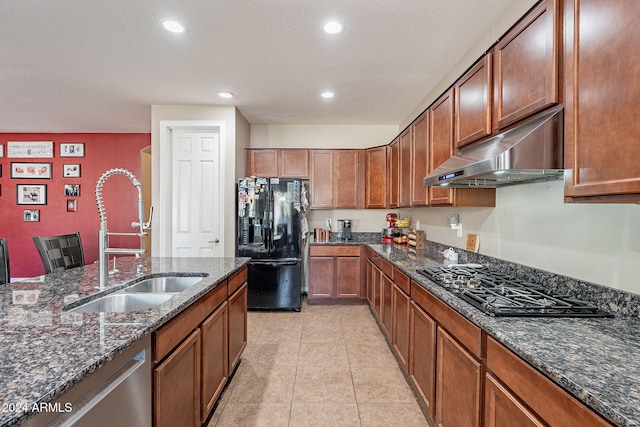 kitchen featuring a textured ceiling, sink, black appliances, dark stone countertops, and light tile patterned flooring