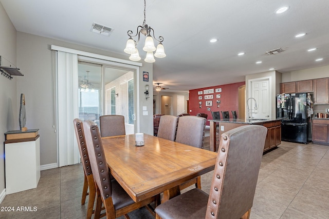 tiled dining space with ceiling fan with notable chandelier and sink