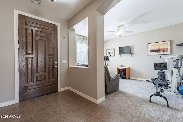 foyer entrance with ceiling fan and carpet