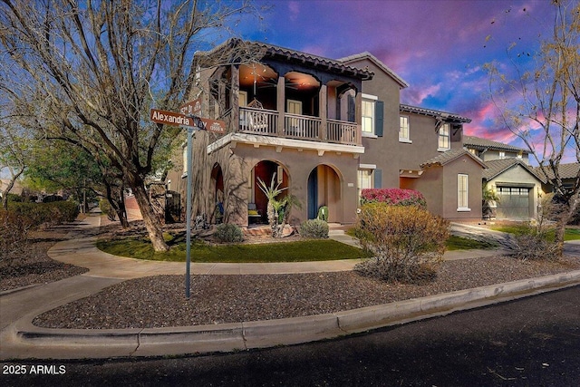 mediterranean / spanish-style home with a tile roof, a balcony, and stucco siding