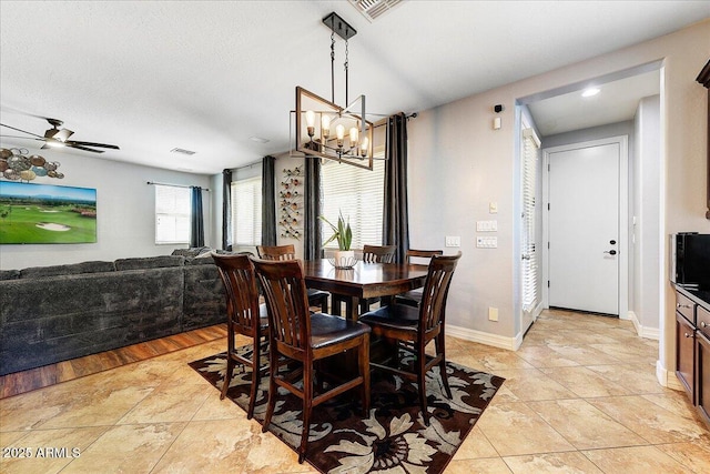 dining room featuring ceiling fan with notable chandelier, visible vents, baseboards, and light tile patterned flooring