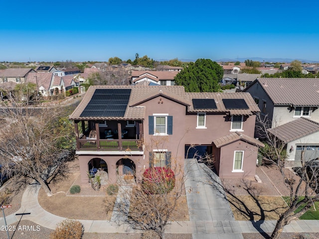 view of front of property featuring stucco siding, a balcony, a residential view, driveway, and a tiled roof