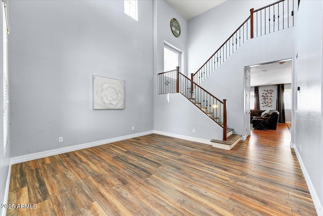 interior space featuring plenty of natural light, a towering ceiling, and wood finished floors