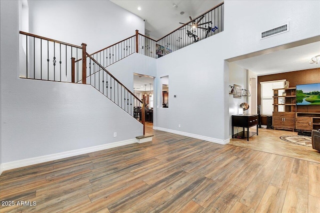 living area featuring visible vents, stairway, baseboards, and wood finished floors