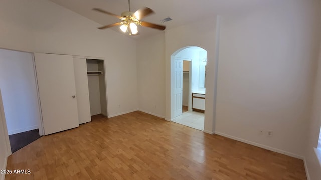 6784 W Gardenia Ave, Glendale, AZ 85303 - unfurnished bedroom with visible vents, connected bathroom, arched walkways, light wood finished floors, and vaulted ceiling