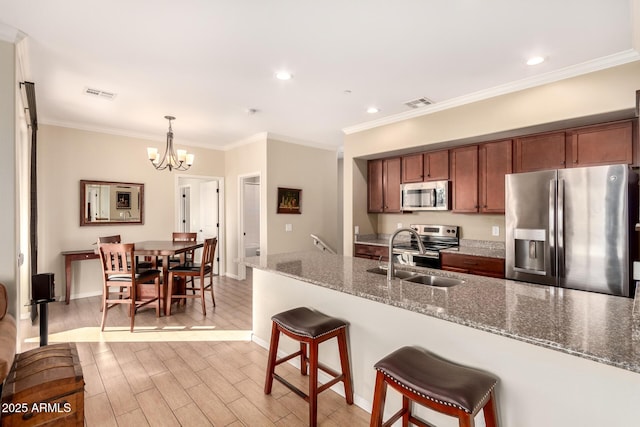 kitchen featuring stainless steel appliances, sink, stone countertops, hanging light fixtures, and a chandelier