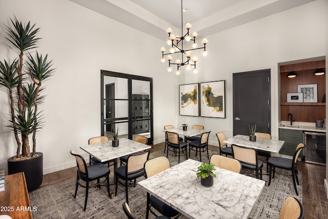 dining area featuring hardwood / wood-style flooring, indoor wet bar, a towering ceiling, and wine cooler