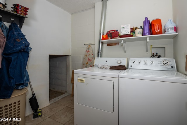 clothes washing area with light tile patterned floors, a textured ceiling, and washer and clothes dryer