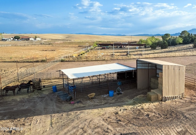 view of horse barn featuring a mountain view and a rural view
