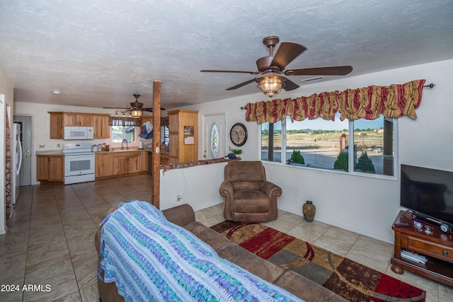 living room with a textured ceiling, ceiling fan, light tile patterned floors, and sink