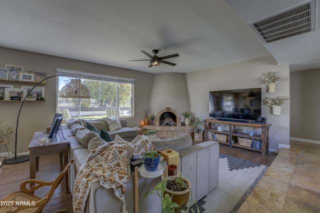 living room with ceiling fan and a fireplace