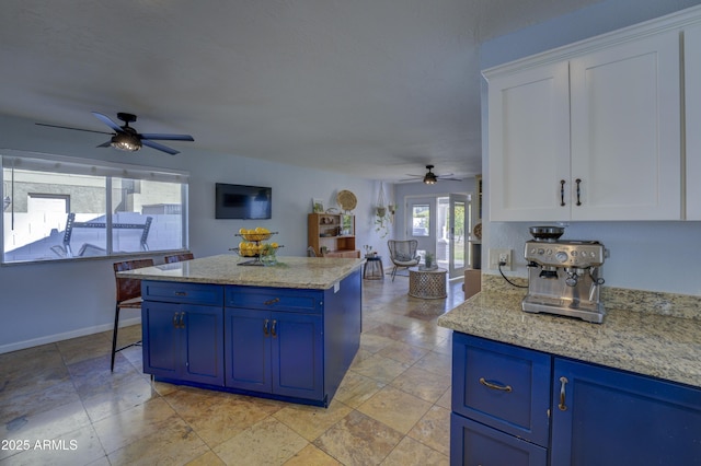 kitchen with french doors, blue cabinetry, light stone counters, white cabinetry, and a breakfast bar area