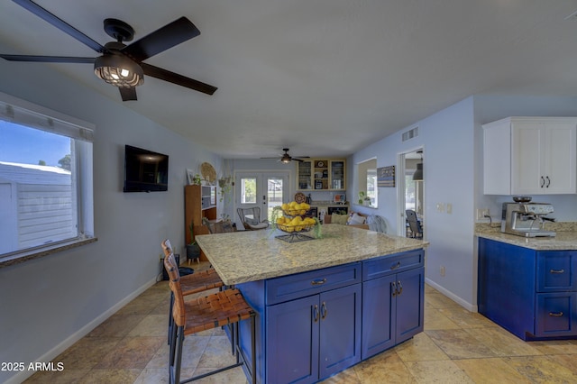 kitchen with a center island, french doors, blue cabinets, light stone counters, and white cabinetry