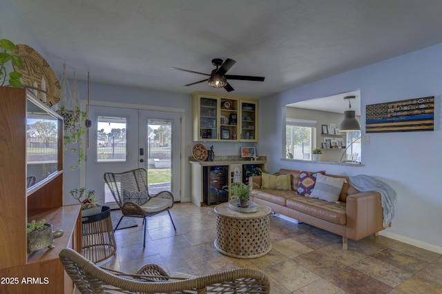 living room with bar area, wine cooler, ceiling fan, and french doors