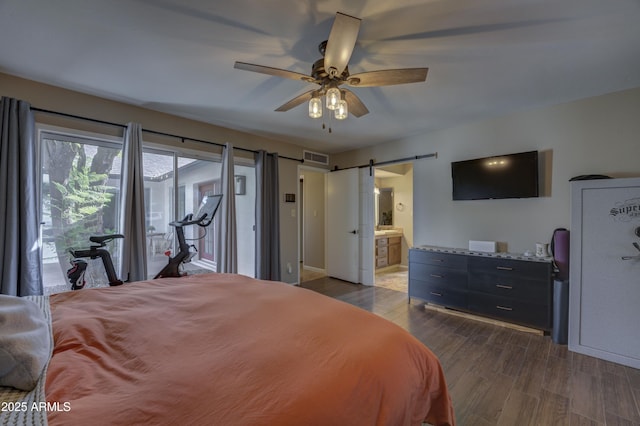 bedroom featuring ceiling fan, a barn door, dark hardwood / wood-style flooring, and access to outside