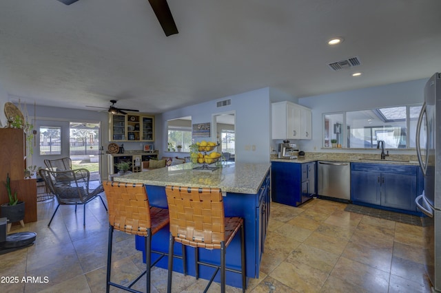 kitchen featuring kitchen peninsula, a kitchen breakfast bar, stainless steel appliances, blue cabinetry, and white cabinets