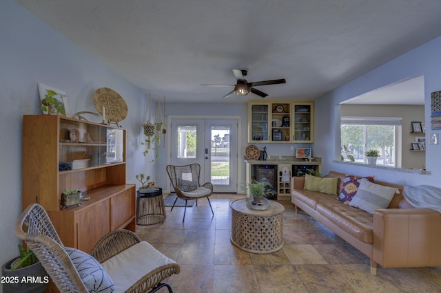 living room with ceiling fan, a wealth of natural light, and french doors