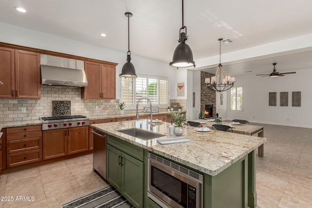 13204 W Palo Verde Dr, Litchfield Park, AZ 85340 - kitchen with stainless steel appliances, a sink, wall chimney exhaust hood, green cabinetry, and backsplash