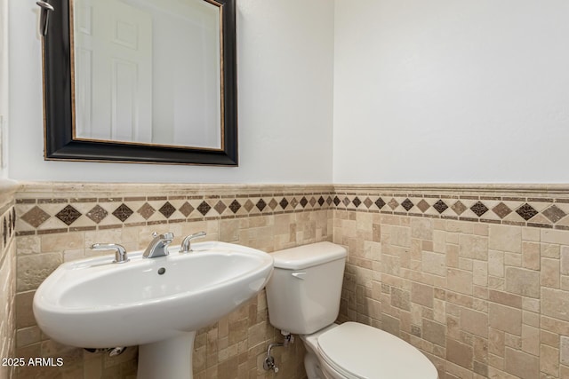 13204 W Palo Verde Dr, Litchfield Park, AZ 85340 - half bathroom featuring tile walls, toilet, wainscoting, and a sink
