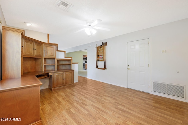 unfurnished living room featuring a textured ceiling, built in desk, light hardwood / wood-style flooring, and ceiling fan