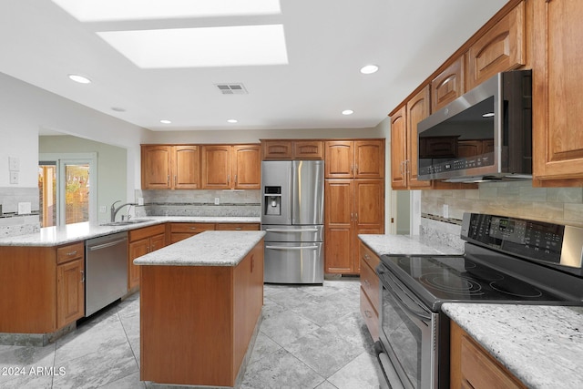 kitchen featuring light stone countertops, a center island, sink, stainless steel appliances, and backsplash