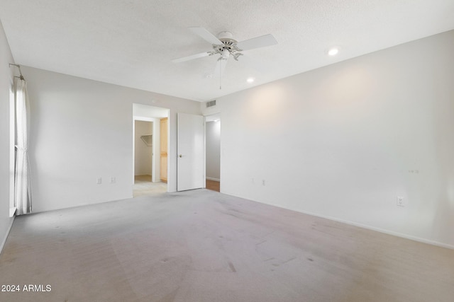 spare room featuring a textured ceiling, light colored carpet, and ceiling fan