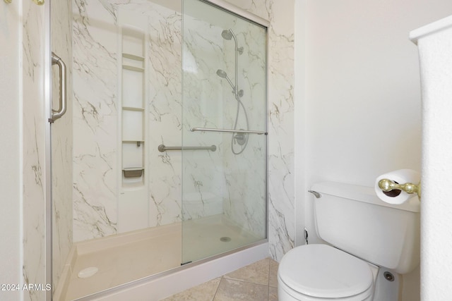 bathroom featuring tile patterned flooring, toilet, and a shower with shower door