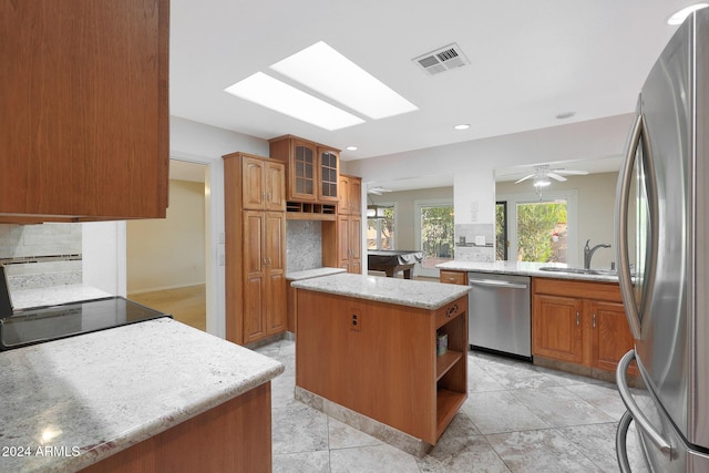 kitchen featuring tasteful backsplash, stainless steel appliances, ceiling fan, sink, and a center island