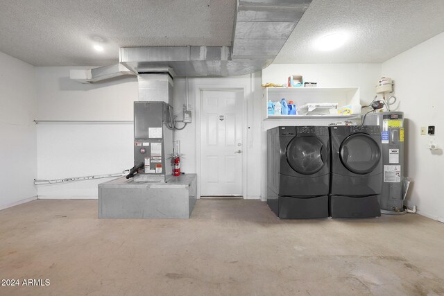 laundry area with heating unit, water heater, washer and dryer, and a textured ceiling