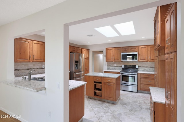 kitchen featuring light stone countertops, tasteful backsplash, stainless steel appliances, sink, and a center island