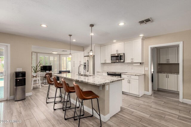 4316 E Janice Way, Phoenix, AZ 85032 - kitchen with appliances with stainless steel finishes, a kitchen bar, light wood-type flooring, plenty of natural light, and recessed lighting