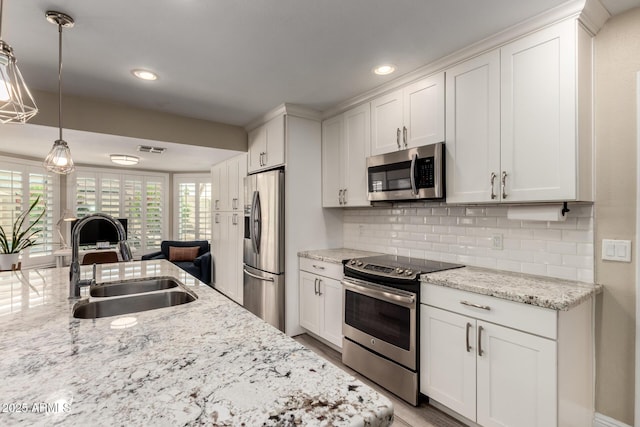 4316 E Janice Way, Phoenix, AZ 85032 - kitchen featuring appliances with stainless steel finishes, a sink, white cabinetry, decorative backsplash, and pendant lighting