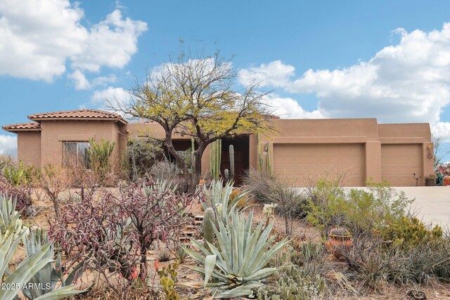 view of front of property with concrete driveway, an attached garage, a tile roof, and stucco siding